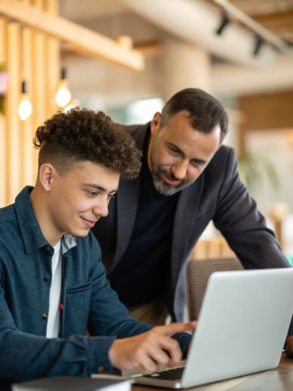 An image of a coach discussing a business plan with a young entrepreneur in a modern office setting, symbolizing Startup Growth Coaching.